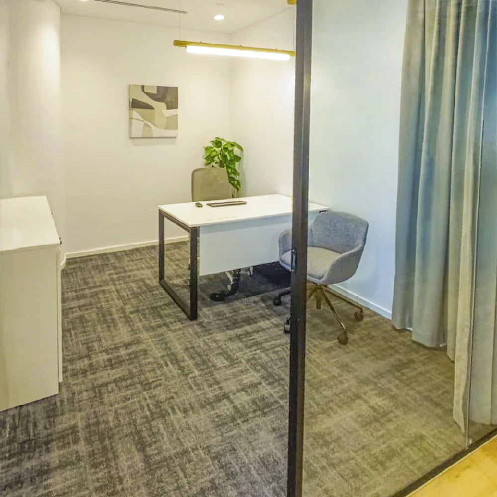 Compact private desk space with soft grey tones and a leafy accent