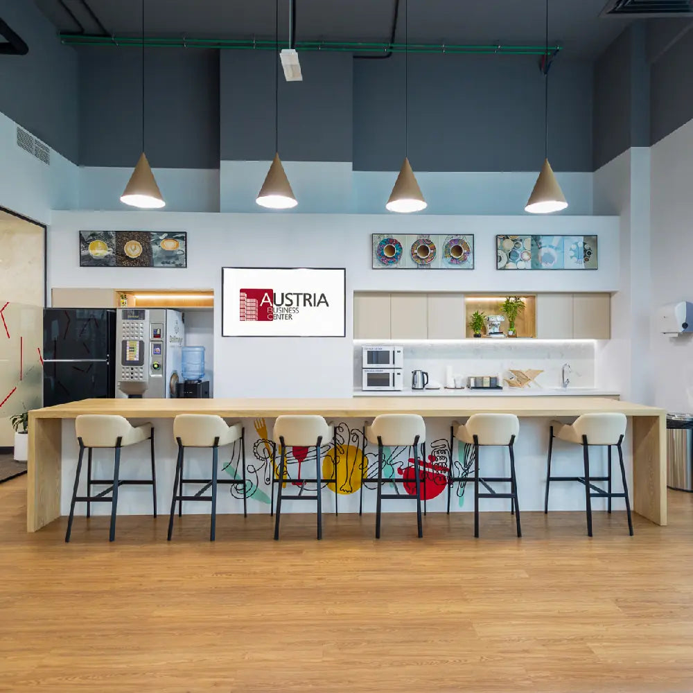 Pantry and coffee bar with high stools and appliances at Austria Business Center, Al Hudaiba Mall.