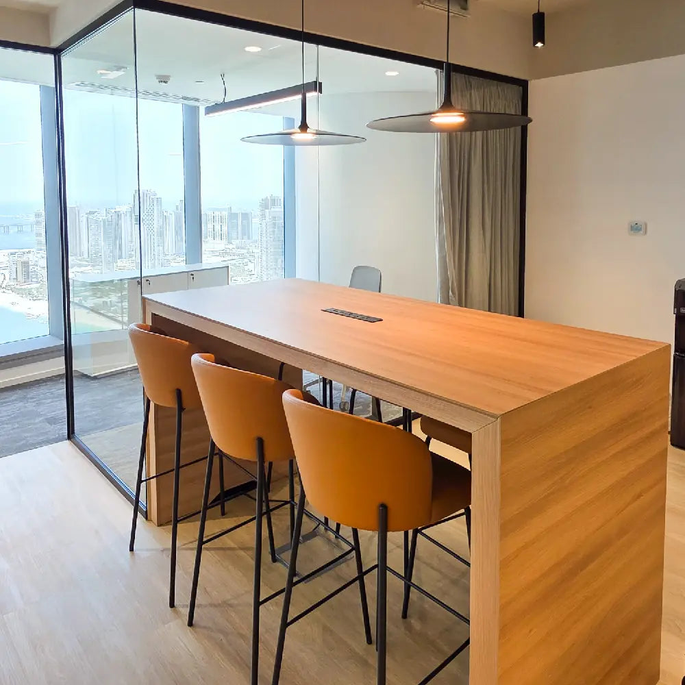 High-top hot desk bar with wood finish and orange seating